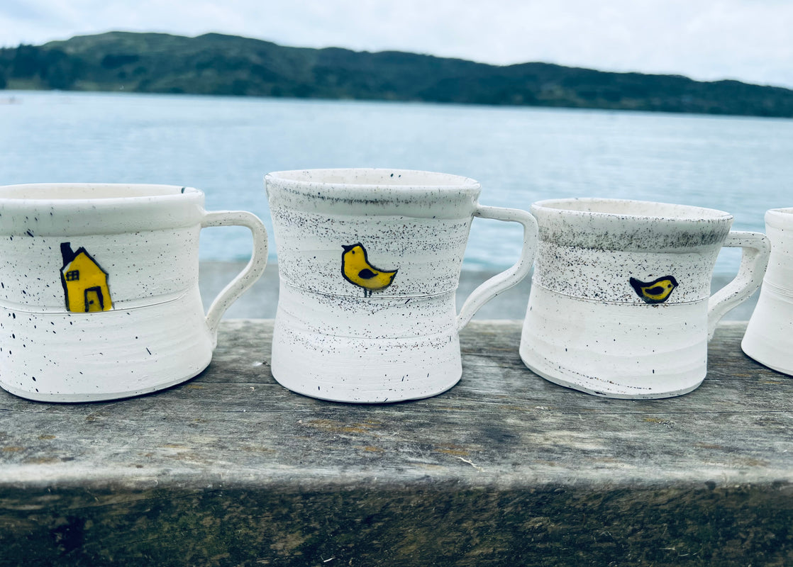 Handmade ceramic mugs with cute house and bird on them